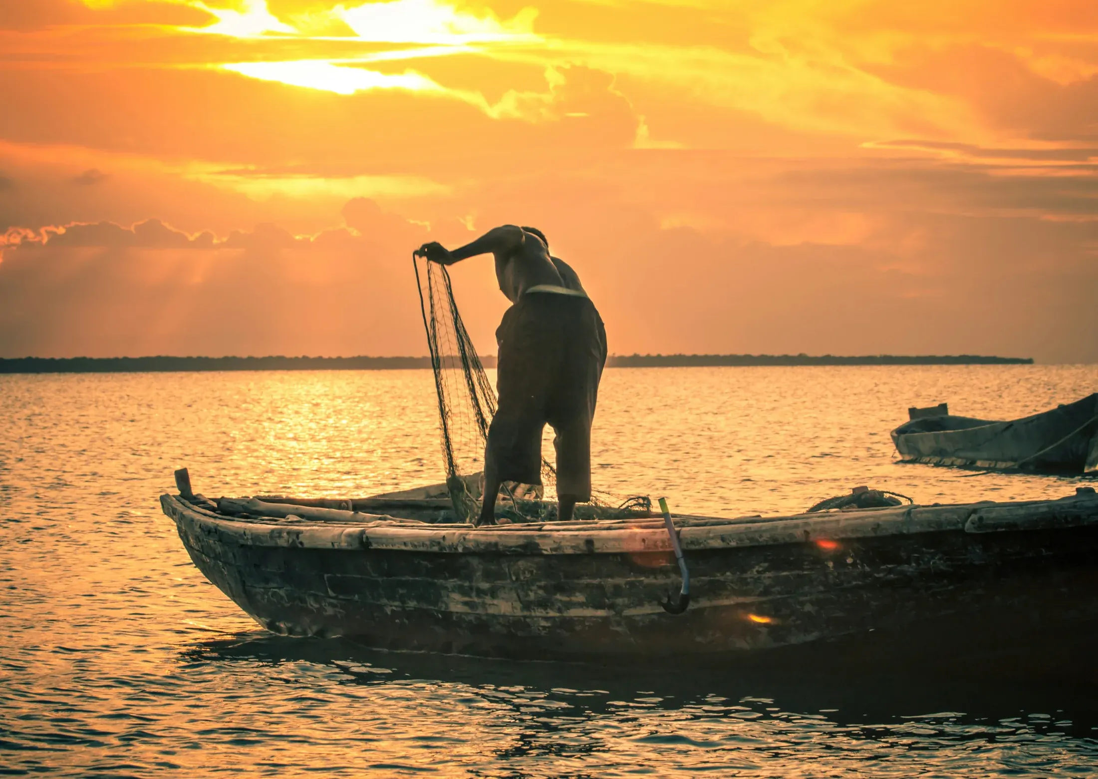Pescador recogiendo su red al atardecer