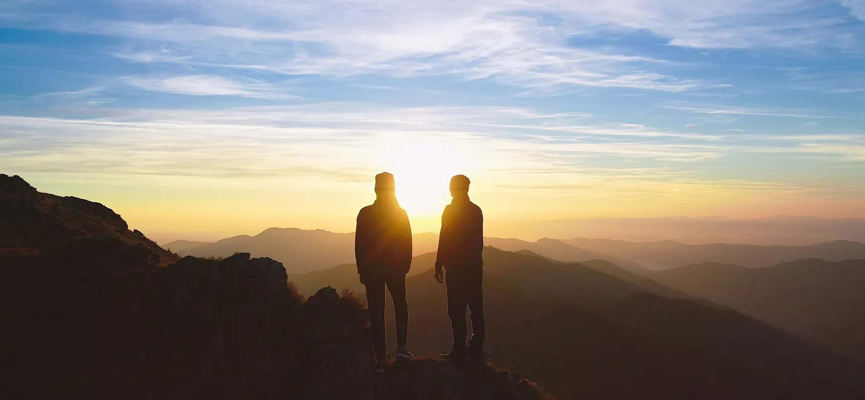 Dos personas mirando el atardecer desde una montaña
